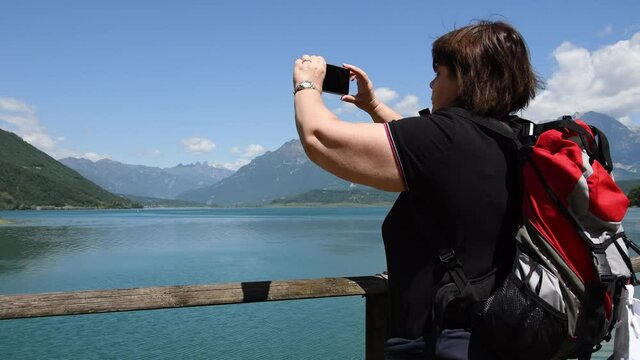 Tourist creates videos with smartphone of the lake of Santa Croce in Farra d'Alpago in the province of Belluno Italy