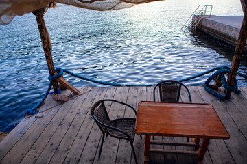 Obraz premium seaside terrace ,wooden pier with a table and chairs 