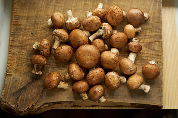 Champignon mushrooms on a wooden board. Fresh healthy brown mushrooms.