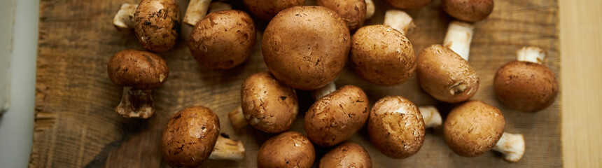 Champignon mushrooms on a wooden board. Fresh healthy brown mushrooms.