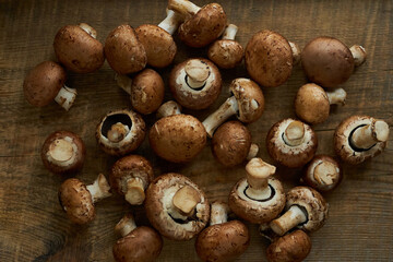 Champignon mushrooms on a wooden board. Fresh healthy brown mushrooms.
