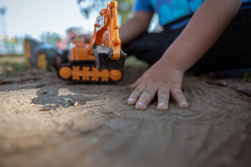 Little kid playing excavator toy on the sand ground