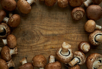 Frame of champignon mushrooms on a wooden background. Champignon mushrooms on a wooden board. Fresh healthy brown mushrooms.