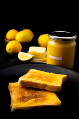 Lemon butter on two pieces of toast, lemons and a jar with a tag which is handwritten 