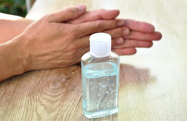 hand rubbing behind alcohol gel for completely cleaning bottle on wooden  table