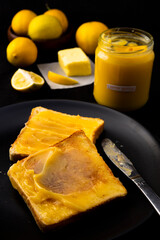 Lemon butter on two pieces of toast, lemons and a jar with a tag which is handwritten 