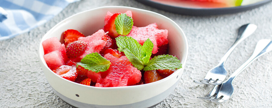 Summer salad with watermelon and strawberry on concrete background table, close-up. Banner image for website