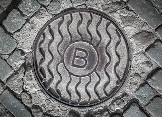 Sewer manhole on a cobblestone road.