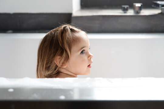 Profile of beautiful toddler girl in bathtub