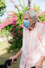 Old woman wearing mask while walking in garden