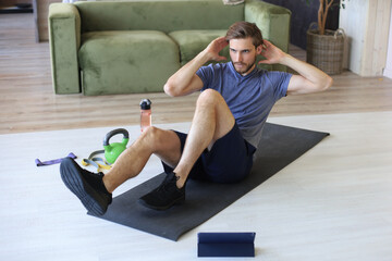 Handsome man doing abs exercises at home during quarantine. Concept of healthy life.