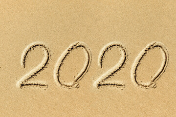 new year 2020 written in sand