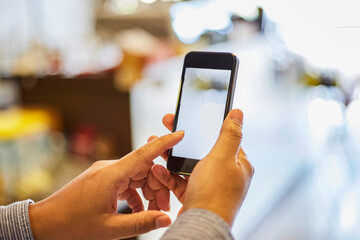 Mobile phone holding by young woman hand isolated on bright abstract blur background. Close up and selective focus.