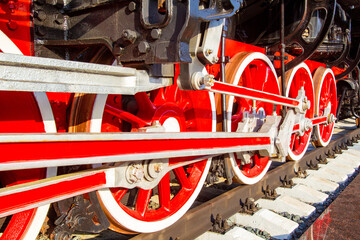 Steam locomotive wheel close up. Train with red wheels. Fragment of a steam locomotive closeup. Red wheels of a vapor train. A steam locomotive rides on rails. Retro. Vintage rail transoprt.