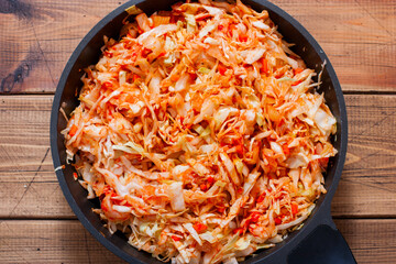 Step-by-step preparation of baked pork shank with cabbage, step 2 - frying cabbage with onions and carrots in a pan, top view, selective focus