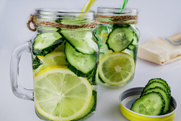 Cold drink, two retro glass jars of lemonade with cucumber and lemon against white background, shallow depth of field, selective focus. Health drink concept.