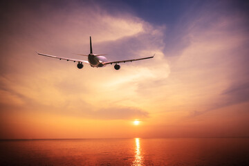 Fototapeta na wymiar Airplane flying over amazing tropical sunset landscape