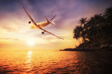Airplane flying over amazing tropical sunset landscape
