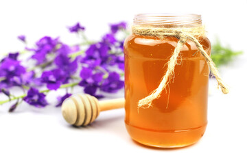 honey dipper, glass jar and wildflowers isolated on white