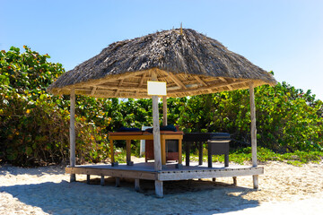 Cuba. A canopy with sunbeds for relaxation. A canopy with a roof made of palm leaves. Beach by the sea. Sandy beach of the Caribbean coast. Sunbeds for massage. Tour to the Republic of Cuba