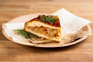 pie with stewed cabbage and carrots sprinkled with herbs on a disposable plate