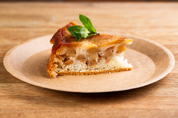 pie with apples and a leaf of mint. Charlotte on a disposable plate
