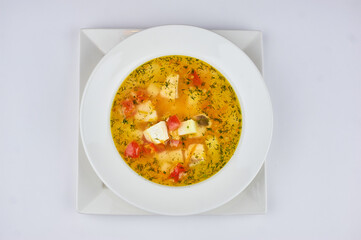 soup with potatoes, cheese, tomatoes and greens on a white background