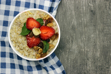 Oatmeal with strawberries, banana and mint on a checkered tablecloth