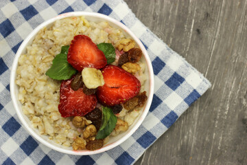 Oatmeal with strawberries, banana and mint on a checkered tablecloth