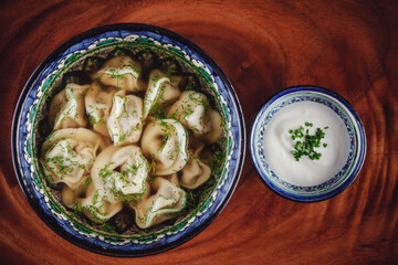 Traditional russian pelmeni, ravioli, dumplings with meat on wooden background.