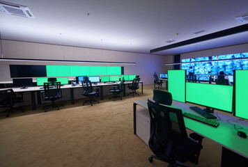 Empty interior of big modern security system control room with blank green screens