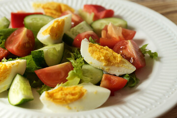 rustic summer salad with fresh cucumbers, tomatoes and eggs on a white plate. the view from the top