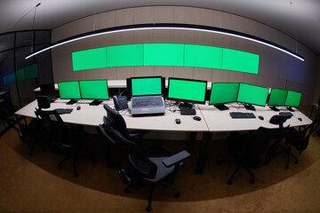 Empty interior of big modern security system control room with blank green screens