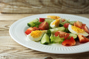 rustic summer salad with fresh cucumbers, tomatoes and eggs on a white plate
