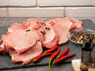 Raw pork steaks on a marble board with spices