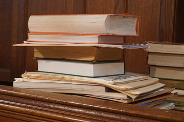 A pile of books stacked on top of one another against a background of oak panelling
