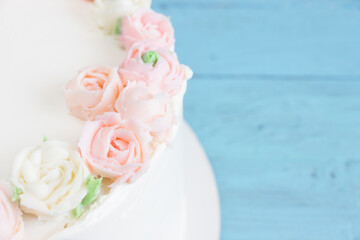 Beautiful cake with pink and white creame roses.Wooden board, blue background, empty space