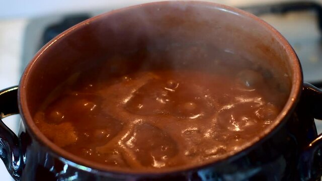 il rag&ugrave; bolle nella pentola di terracotta