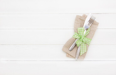 Table setting .Close up Fork and Knife  on  napkin ,empty space. Spring table setting with green ribbon