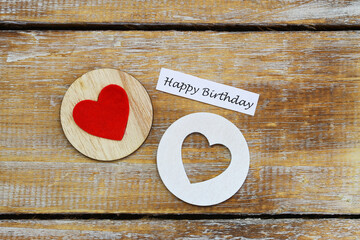 Happy birthday card with two wooden hearts on rustic surface
