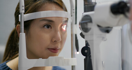 Woman checks her eyes in clinic © leungchopan
