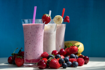 fresh fruit smoothie milkshake with berries blue background