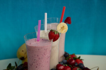 fresh fruit smoothie milkshake with berries blue background