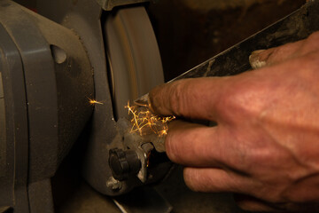 A man's hand with dirty fingers holds a knife. The iron knife is sharpened with a special...