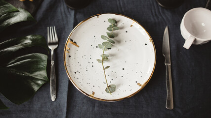 plate with cutlery on a black table and green leaves
