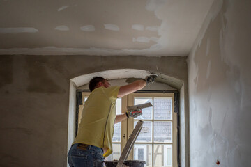  craftsman plastering a lintel with mortar on a building site.