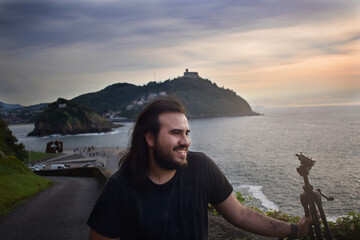Fot&oacute;grafo posando para una foto con un paisaje de atardecer de fondo
