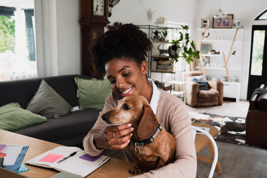 Woman working from home with her puppy on her lap