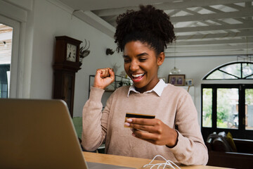 Young female happily making an online credit card payment from home, online shopping