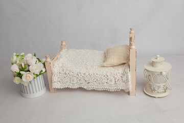  flowers next to wooden pastel baby bed with decor in white baby's room, copy space concept. Stylish baby bed near light wall in interior of children's room. 